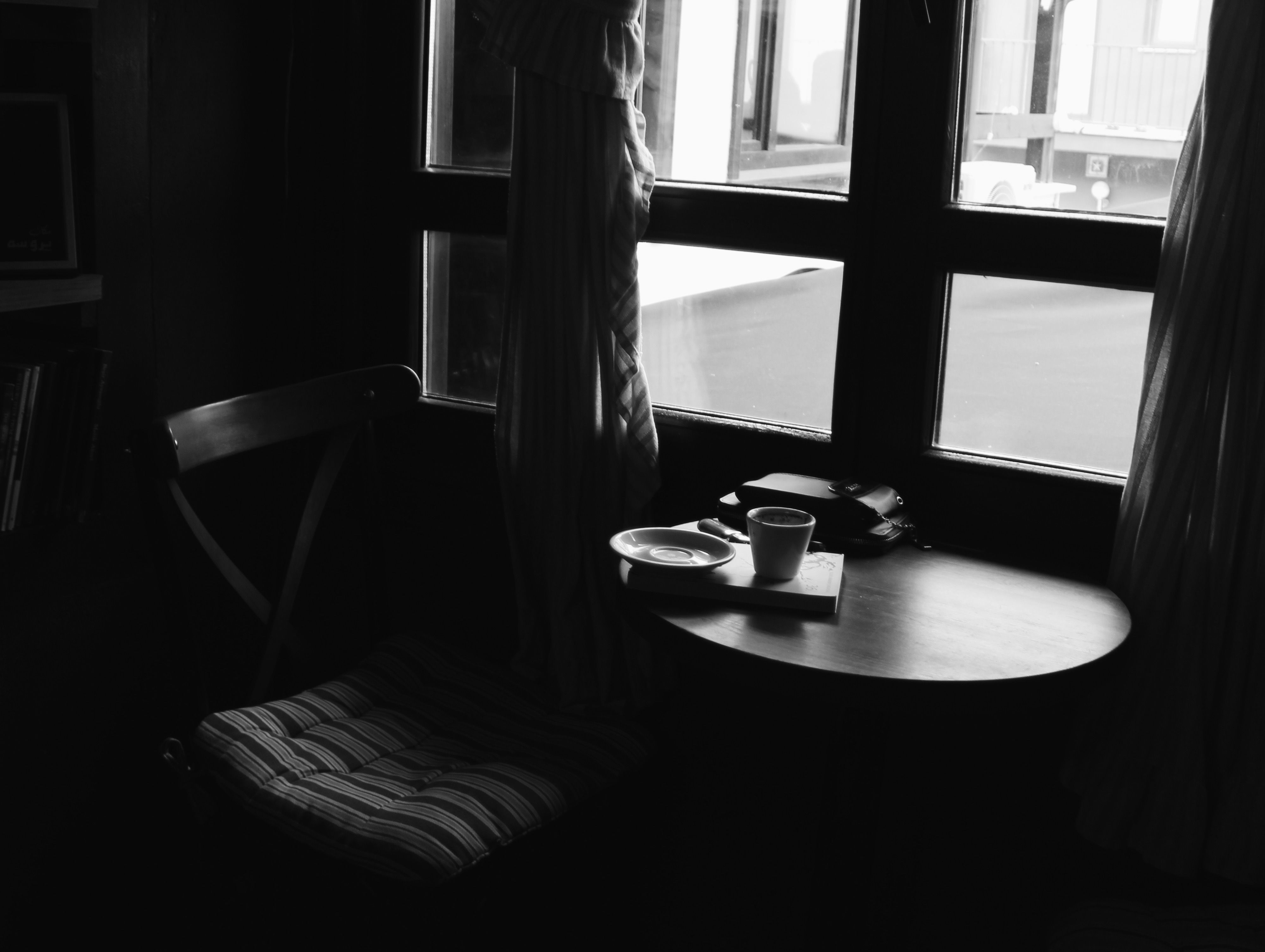 A coffee cup and opened newspaper on a wooden table, morning light streaming through a nearby window.