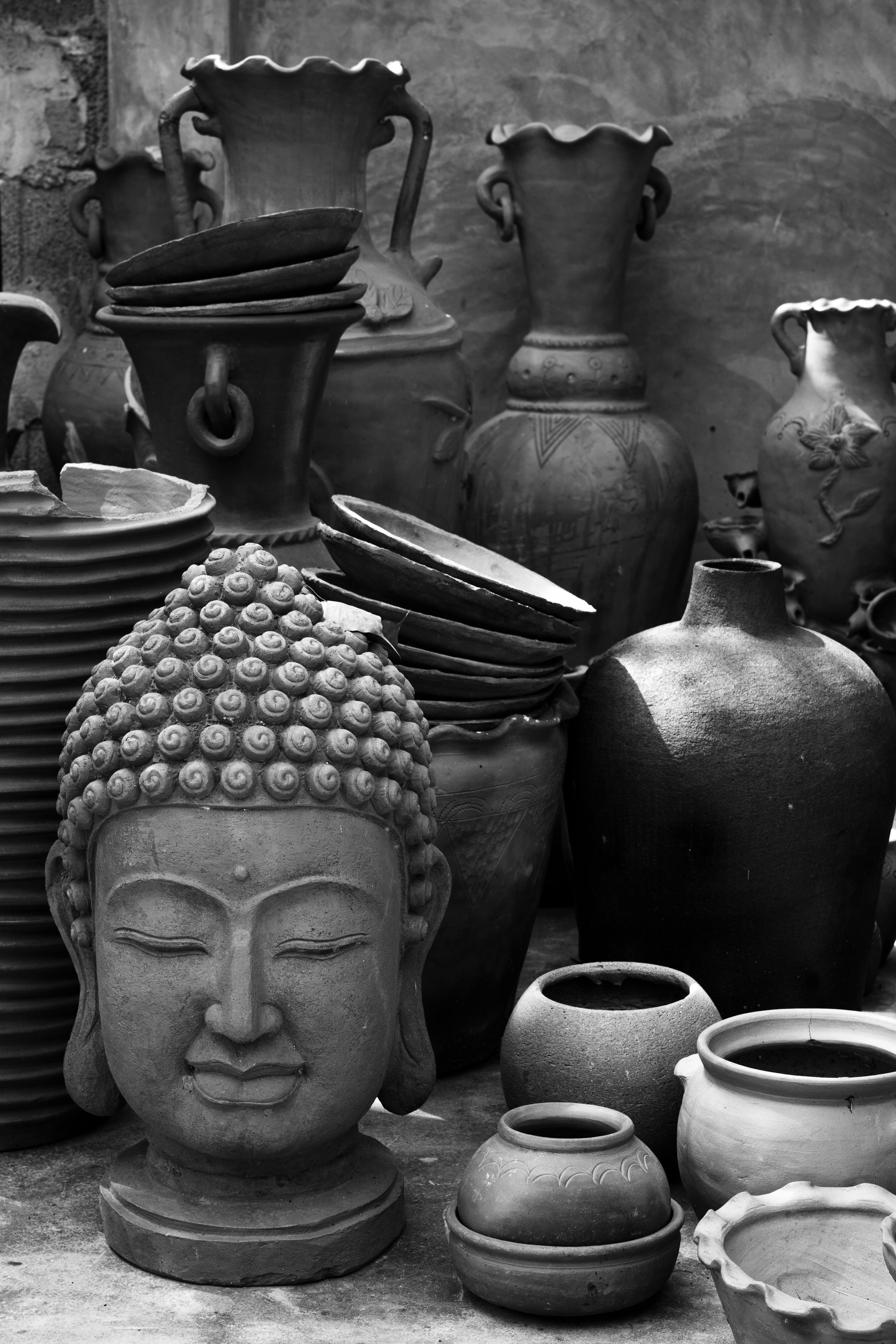 A still life arrangement of ceramic vessels and folded linen under soft, directional light.